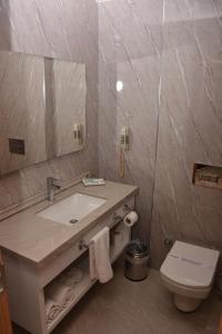 bagno con lavandino, servizi igienici e specchio di Othello Hotel a Mersin