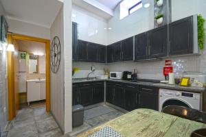 eine Küche mit schwarzen Schränken und einer Spüle in der Unterkunft Casa da Escola in Cacia + 26 Fotos