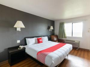 a bedroom with a large bed with a red and white blanket at OYO Hotel Irving DFW Airport North in Irving