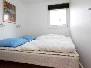 a white bed with blue pillows in a room at 8 person holiday home in V ggerl se in Marielyst