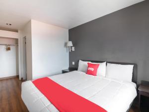 a bedroom with a large white bed with red pillows at OYO Hotel Irving DFW Airport North in Irving