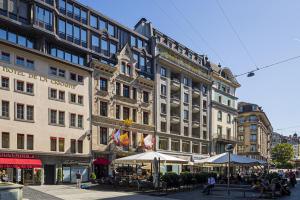 a large building with tables and umbrellas in a city at Hôtel de la Cigogne in Geneva