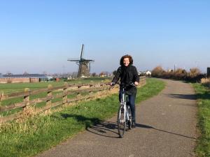 a woman riding a bike down a road with a windmill at Appartementen Casa del Lago in Lisse