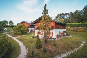 a house with a tree in the middle of a yard at Pineta Nature Resort - Wellness & SPA in Coredo