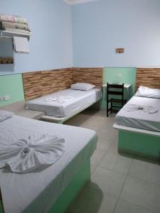a room with two beds and a table with a chair at POUSADA DOS AMIGOS in Presidente Venceslau