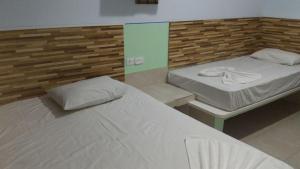 two twin beds in a room with a wall at POUSADA DOS AMIGOS in Presidente Venceslau