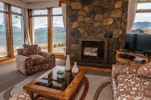 sala de estar con chimenea de piedra y TV en Hotel Capitán Eberhard, en Puerto Natales