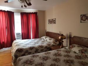 a bedroom with two beds and red curtains at At the Harbourfront B & B in North Sydney