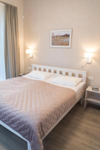 a large bed in a bedroom with two lights on at Green Hill Apartments in Kaunas