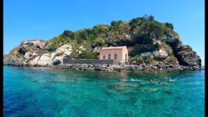 a group of people swimming in the water near a house at Casa Galatea in Acitrezza