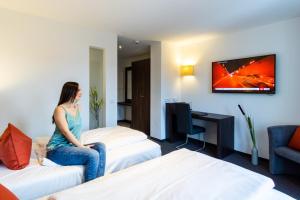 a woman sitting on two beds in a hotel room at Hotel DuDa Langenbruck 3-Sterne-Superior-Hotel an der A9 zwischen Ingolstadt und München in Langenbruck +65 photos