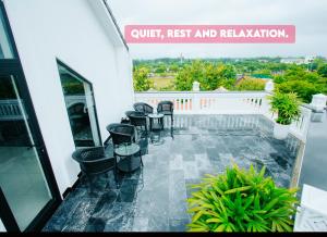 a balcony with chairs and tables on a building at Hoianation Villas Hotel in Hoi An