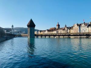 een brug over een rivier in een stad met gebouwen bij Swiss Dewa in Luzern