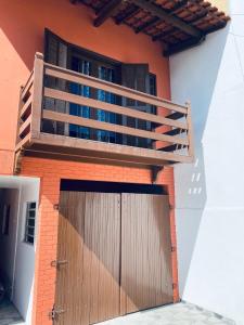 a house with a wooden garage door and a balcony at Meus Guris in Arraial do Cabo