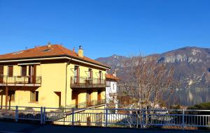 een geel huis met een hek naast een meer bij Il Terrazzino sul Lago in Bellagio