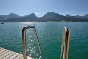 a boat on a lake with mountains in the background at Hotel Zimmerbräu in St. Wolfgang