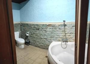 a bathroom with a bath tub and a toilet at Hana Kuta Beach Hotel in Kuta