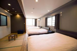 ein Hotelzimmer mit 3 Betten und einem TV in der Unterkunft TABISAI HOTEL Premium 博多-中洲 in Fukuoka