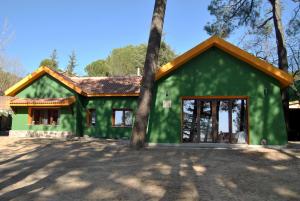 um edifício verde com uma árvore em frente em Casa Rural Villa Angeles con Piscina y Jacuzzi em Collado Mediano