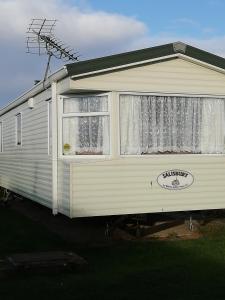 an rv parked in a yard with a window at Lovely 4 berth static caravan, Marine Holiday Park, Rhyl, Wales in Rhyl