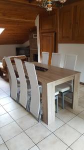 a dining room table with white chairs around it at Le repaire du deux roues in Saint-Sauveur