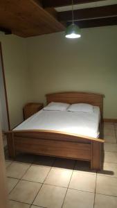 a bedroom with a wooden bed with white sheets at Le repaire du deux roues in Saint-Sauveur