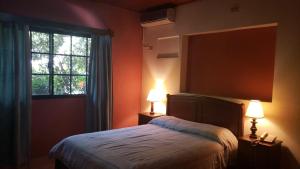 una camera da letto con un letto con due lampade e una finestra di Hotel Alsacia a Tegucigalpa
