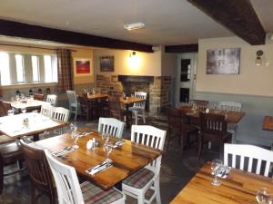 a restaurant with wooden tables and chairs and a fireplace at The Griffin Inn in Halifax