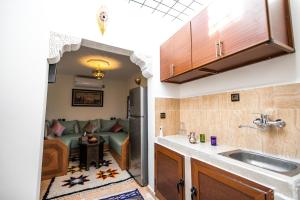 uma cozinha com um lavatório e uma sala de estar com um sofá em Apartment Lala Rkia em Fez