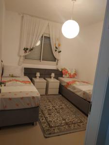 a small bedroom with two beds and a window at עכו דירה חדשה ליד הים- Akko-brand new apartment in ‘Akko