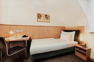 a hotel room with a bed and a desk at Pension Kasper in Vienna