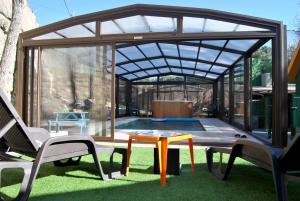 a pavilion with a table and chairs and a pool at Complejo Casas Rurales MANSIONES Y VILLAS DELUXE in Collado Mediano