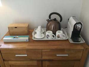 a tray with a tea kettle and cups on a cabinet at Maison d Hôtes La Petite Jucherie in Saint-Hippolyte