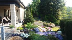 un jardín con flores púrpuras y púrpuras frente a una casa en KAMA Ferienhäuser Haus Kathrin, en Wendisch Rietz