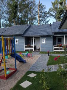 ein Haus mit einem Spielplatz davor in der Unterkunft Domki na Leśnej in Ustronie Morskie