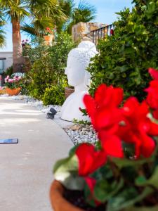 uma estátua branca sentada ao lado de algumas flores vermelhas em Casa Olina em Bahia de Casares