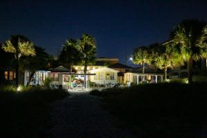 une maison éclairée la nuit avec des palmiers dans l'établissement 5 - Seahorse Cottages, à St. Pete Beach