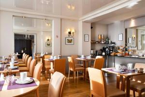 a restaurant with tables and chairs and a counter at Hôtel de Genève in Paris