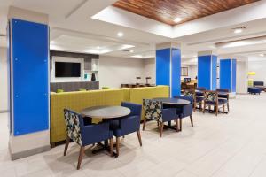a waiting area with tables and chairs in a lobby at Holiday Inn Express Hotel & Suites Dothan North, an IHG Hotel in Dothan