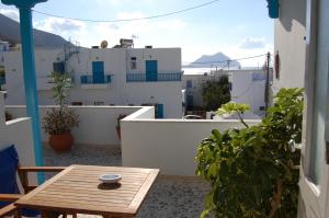 a small wooden table on a balcony with white buildings at Aegeon Pension in Aegiali
