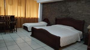 HOTEL PUERTA DEL SOL في سانتو دومينغو دا لوس كولورادوس: غرفة نوم بسريرين وجدار من الطوب