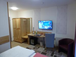 Zimmer mit einem Schreibtisch und einem TV an der Wand in der Unterkunft Landhotel Auerose Garni in Neu Kosenow