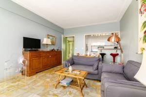 a living room with a couch and a tv at Appartement Bagatelle Exceptional location with stunning sea views in Juan-les-Pins