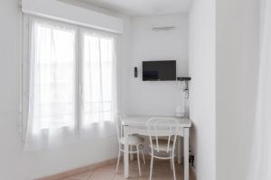 una sala da pranzo bianca con un tavolo e due sgabelli di Studio Bella Nissa - Welkeys a Nizza