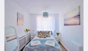 ein weißes Schlafzimmer mit einem Bett mit blauer Bettwäsche und Kissen in der Unterkunft Super location 1min from metro 10min from Camden in London