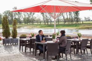 Ein Mann und eine Frau, die an einem Tisch unter einem Schirm sitzen in der Unterkunft Hotel & Restaurant Gasthaus Zum Anker in Elster