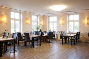 Hotel & Restaurant Gasthaus Zum Anker في Elster: مطعم بالطاولات والكراسي والناس جالسين عندهم