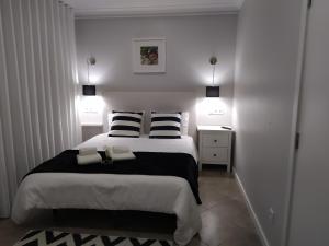 Schlafzimmer mit einem Bett mit schwarzen und weißen Kissen in der Unterkunft FerhouseDreams-Praia in Nazaré