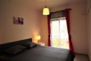 T1+1 Praia da Rocha/ Gaivota Mar 5 في بورتيماو: غرفة نوم بسرير ونافذة ذات ستائر حمراء +33 صورة