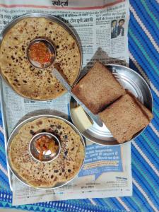 a newspaper with three bowls of soup and a sandwich at Varah Square Guest House in Pushkar